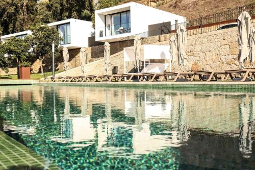 a house is reflected in the water of a swimming pool at Portovella Lodges & Bungalows in Pala