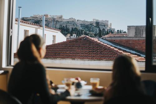 a group of people sitting at a table looking out a window at Muse Urban Suites in Athens