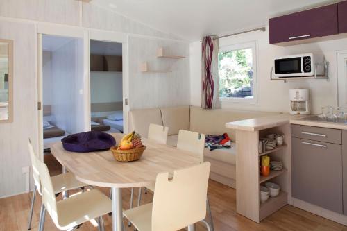une cuisine et une salle à manger avec une table et des chaises dans l'établissement Camping du Val de l'Eyre, à Salles