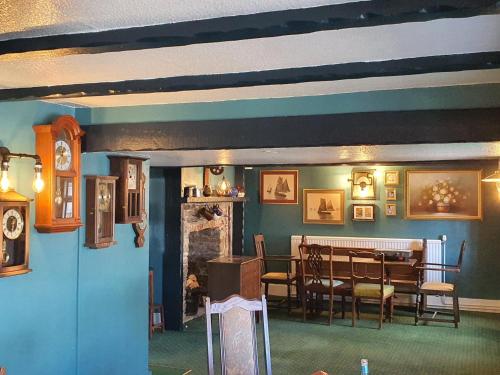 a dining room with a table and chairs and a room with a fireplace at The Harbour Moon in Looe