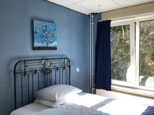 a bed in a blue bedroom with a window at Vredig Toeven in Klaaswaal