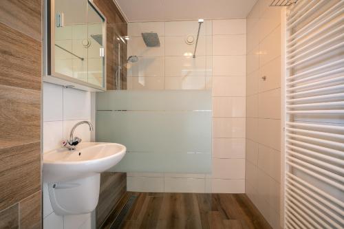 ein weißes Bad mit einem Waschbecken und einer Dusche in der Unterkunft Annabella 13 in De Koog