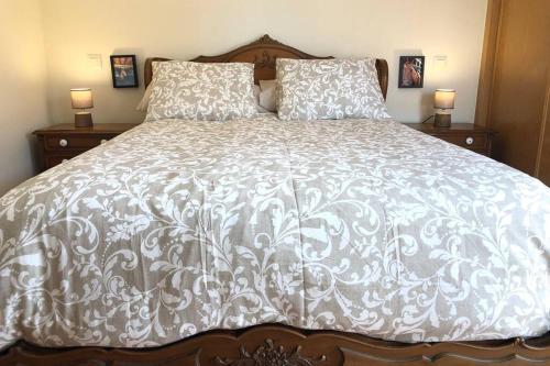 a bed with a white comforter and two pillows at Tu Casa Ecuestre in Villavieja del Lozoya