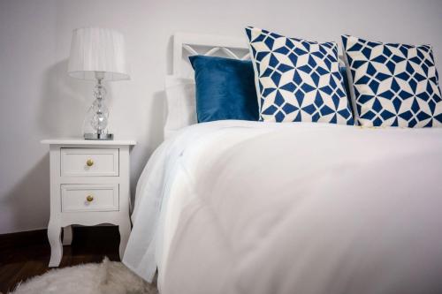 a bed with blue and white pillows and a night stand at Casa A Boleriña in Combarro