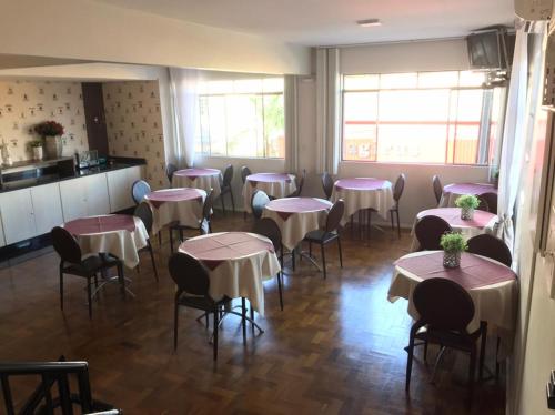a dining room with tables and chairs and windows at Hotel Requinte in Dois Vizinhos