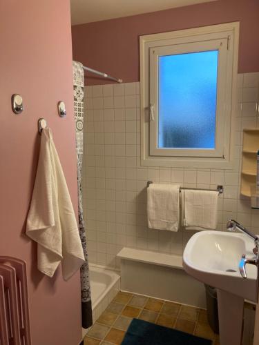 ein Bad mit einem Waschbecken, einer Badewanne und einem Fenster in der Unterkunft MON DADA in Granville