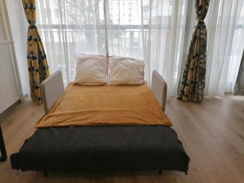 a bed sitting in front of a window with curtains at Exotika - appartement de charme, Rouen in Rouen