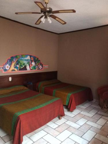 a hotel room with two beds and a ceiling fan at Hotel Regis in Uruapan del Progreso