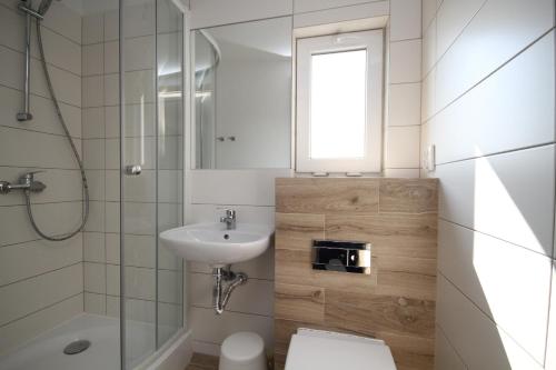 a bathroom with a sink and a toilet and a mirror at Pokoje Gościnne Lidia Łeba in Łeba