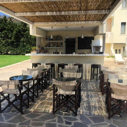 a patio with a bar and tables and chairs at Aphrodite Samos Suites in Marathokampos