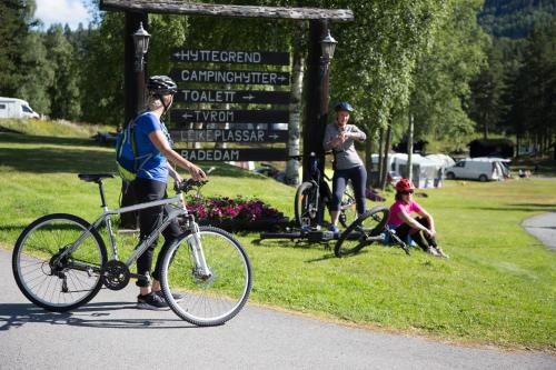 una persona con una bicicleta delante de un cartel en Groven Camping & Hyttegrend, en Åmot