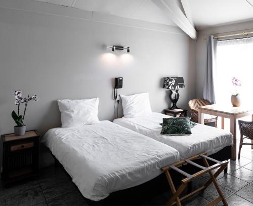 1 dormitorio con 2 camas, mesa y ventana en Hotel Pacific en Weelde