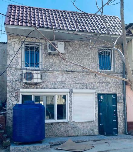 a stone house with a blue barrel in front of it at Дом - дача in Chornomorsk