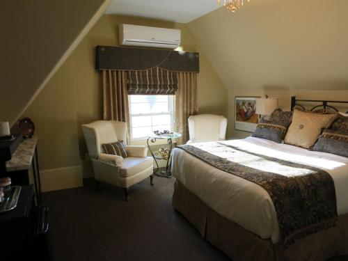 a bedroom with a bed and a chair and a window at The Woodview Inn in Gananoque