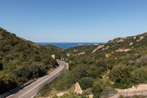 una strada tra le colline con l'oceano sullo sfondo di Homey Experience - Emerald Valley Sea View a Porto Cervo