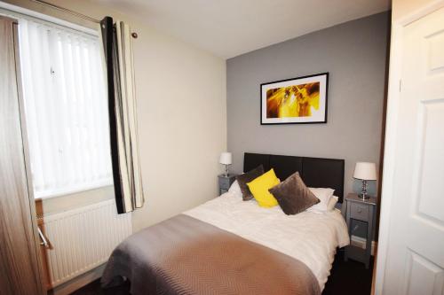 a bedroom with a bed with yellow pillows and a window at The Retreat in Blackpool