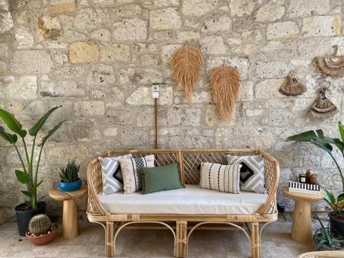 a wicker couch in front of a stone wall with plants at Aliko Hotel in Alacati