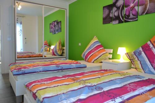 2 Betten in einem Zimmer mit grünen Wänden und Spiegeln in der Unterkunft Loft Apartments Pulheim in Pulheim