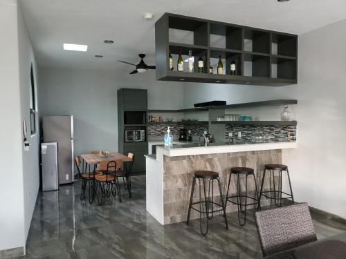 a kitchen with a bar with stools and a table at Casa Sandy in Cozumel