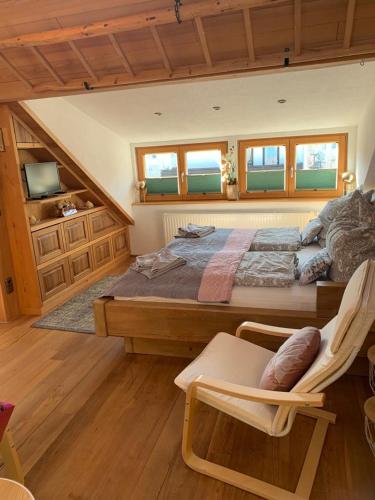a bedroom with a large bed with a chair and windows at Ferienhaus Elisabeth in Füssen