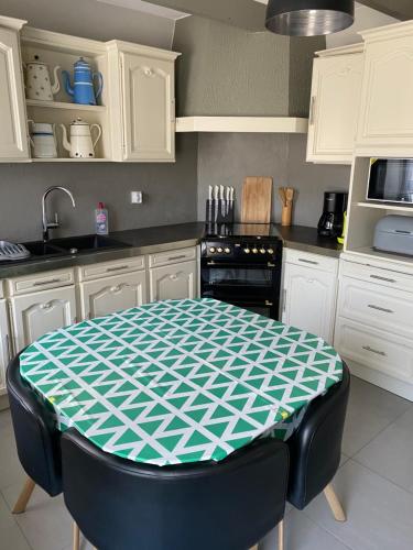 - une cuisine avec une table verte et blanche dans l'établissement La Petite Maison, à Saint-Nicolas-du-Pélem