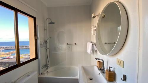 een badkamer met een bad, een wastafel en een spiegel bij Apt con piscina Playa Roja, La Restinga(El Hierro) in La Restinga