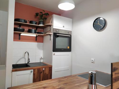 une cuisine avec un évier et une horloge murale dans l'établissement LASAIA St Esprit T3 proche Adour, à Bayonne