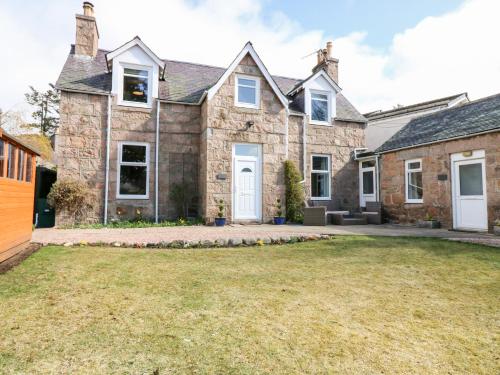 a large stone house with a yard at Gairnlea House in Ballater