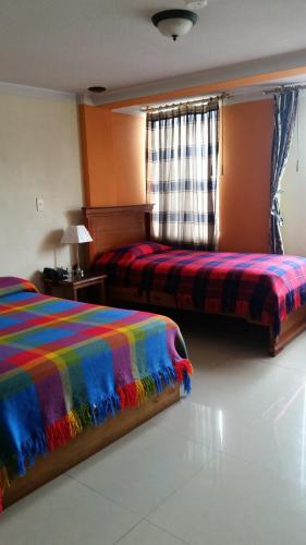 a bedroom with two beds with a colorful blanket at Las Garzas Alojamiento in Ibarra