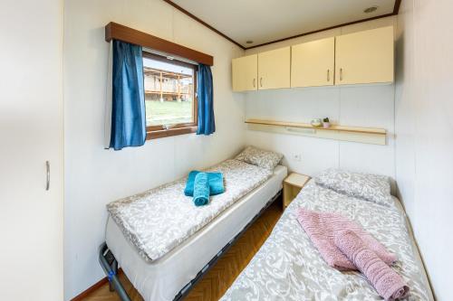 2 Betten in einem kleinen Zimmer mit Fenster in der Unterkunft Mobilheim Chalet - Výrovická přehrada in Výrovice