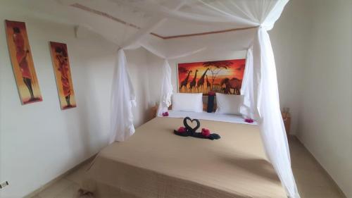 a bedroom with a bed with white curtains and a painting at Maisha Marefu Apartments in Kiwengwa