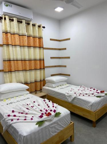 two beds in a room with flowers on them at La Luna Boutique Dhangethi in Dhangethi