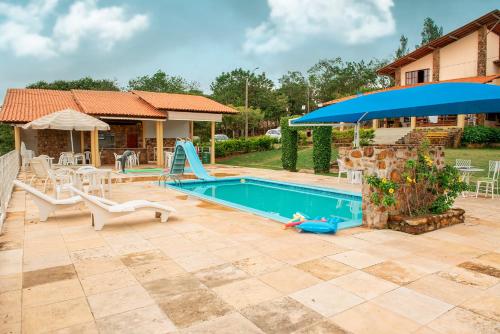 a swimming pool with a slide and an umbrella at Pousada Calugi in Triunfo