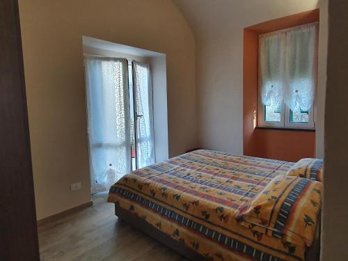 ein Schlafzimmer mit einem Bett und zwei Fenstern in der Unterkunft La Casa degli Archi in Tavarone