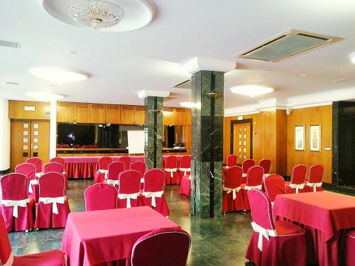 una sala conferenze con tavoli e sedie rossi di Hotel Imperial a Valladolid