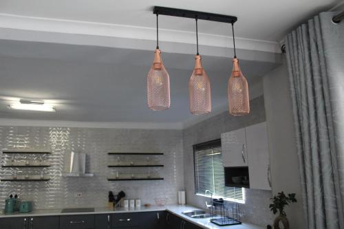 a kitchen with three glass lights hanging from the ceiling at Villa 13 Maun in Maun