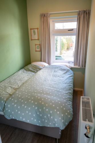 a small bedroom with a bed and a window at iwalani Beach Bungalow - large Private Garden - close to City Center & Beach in De Koog