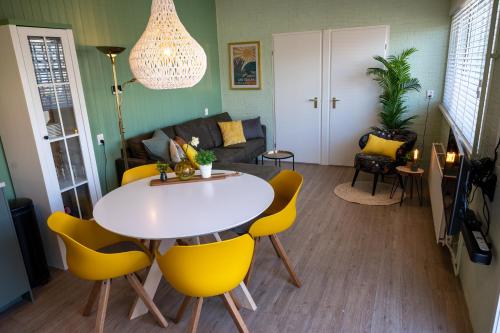 a living room with a table and yellow chairs at iwalani Beach Bungalow - large Private Garden - close to City Center & Beach in De Koog