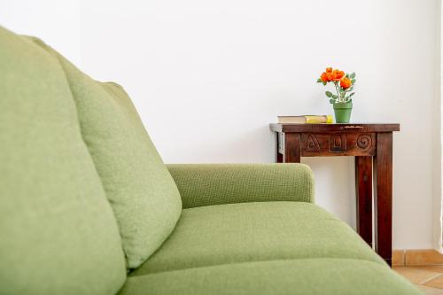 a green couch next to a table with a vase of flowers at Appartamenti Lungoni in Santa Teresa Gallura