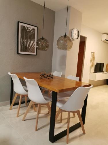 une salle à manger avec une table en bois et des chaises blanches dans l'établissement Naufragos Apartament Torrevieja, à Torrevieja