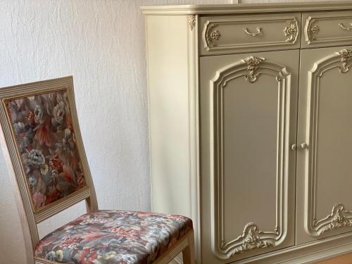 a chair sitting next to a cabinet in a room at 3 Zimmer Ferienwohnung Hellmairs in Landsberg am Lech
