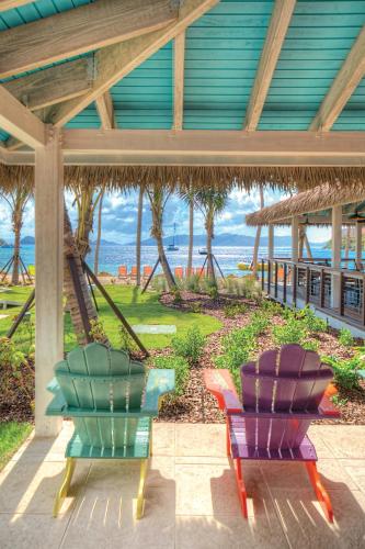 two colorful chairs sitting under a building with the ocean in the background at Margaritaville Vacation Club - St Thomas in Frydendal