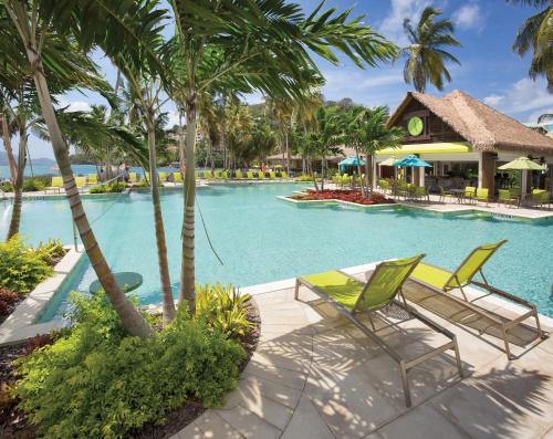 a resort swimming pool with two chairs and palm trees at Margaritaville Vacation Club - St Thomas in Frydendal