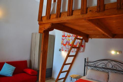 a room with a loft bed with a red couch and a ladder at Beachfront Apartment Kato Zakros in Káto Zákros