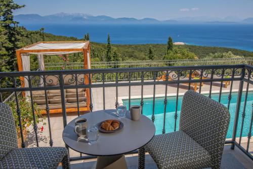 a table with a plate of food on a balcony at Luxury villa above emblisi beach , with heated pool ! in Fiskardho