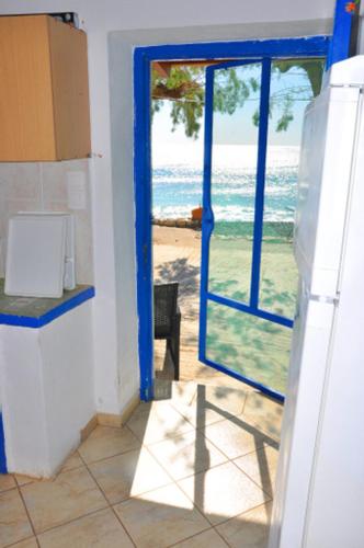 a kitchen with a blue door and a view of the ocean at Beachfront Apartment Kato Zakros in Káto Zákros