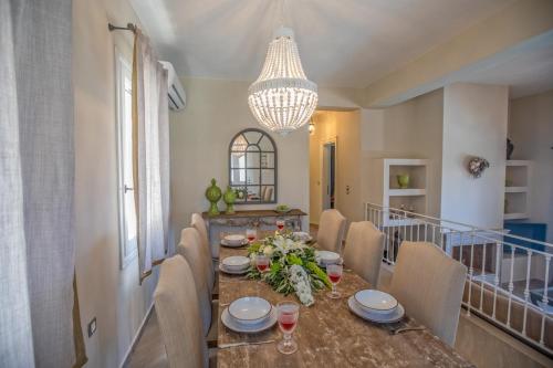 a dining room with a table with chairs and a chandelier at Luxury villa above emblisi beach , with heated pool ! in Fiskardho