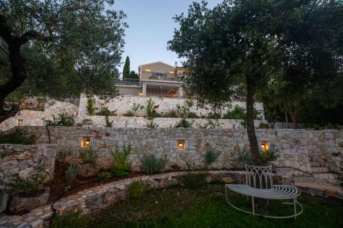 a bench in a yard with a stone wall at Luxury villa above emblisi beach , with heated pool ! in Fiskardho