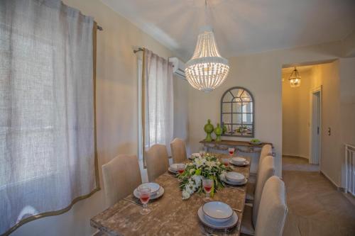 a dining room with a table and chairs and a chandelier at Luxury villa above emblisi beach , with heated pool ! in Fiskardho