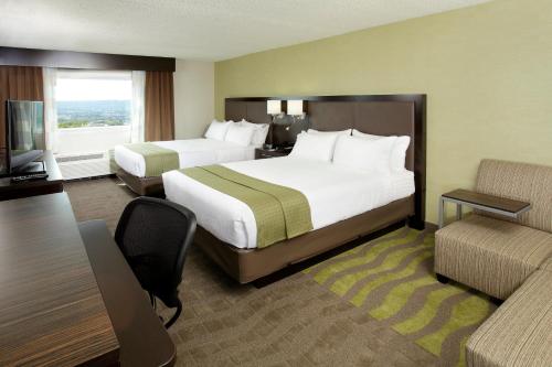a hotel room with two beds and a couch at Holiday Inn Wilkes Barre - East Mountain by IHG in Wilkes-Barre